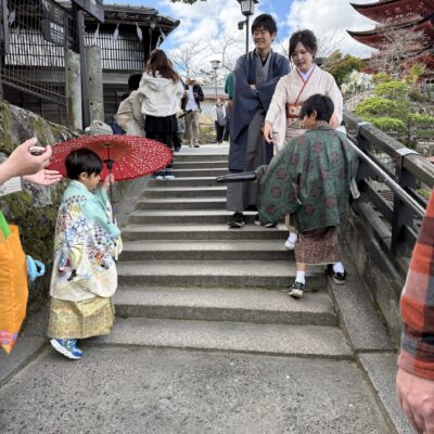 A family in traditional Japanese clothing walks down stone steps near a temple