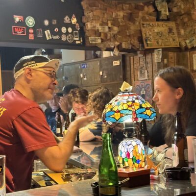 Two people sit at a bar counter having an animated conversation